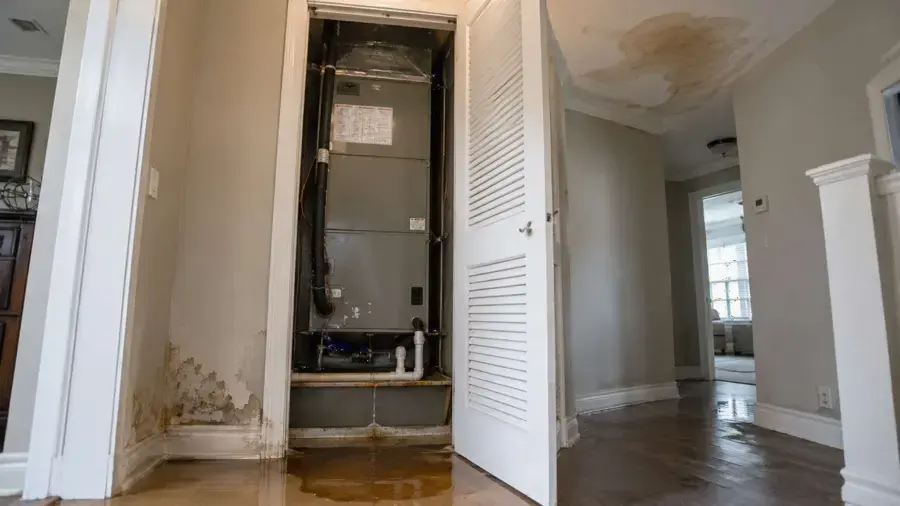 Air handler closet with water-stained walls from a condensate overflow in a Naples home