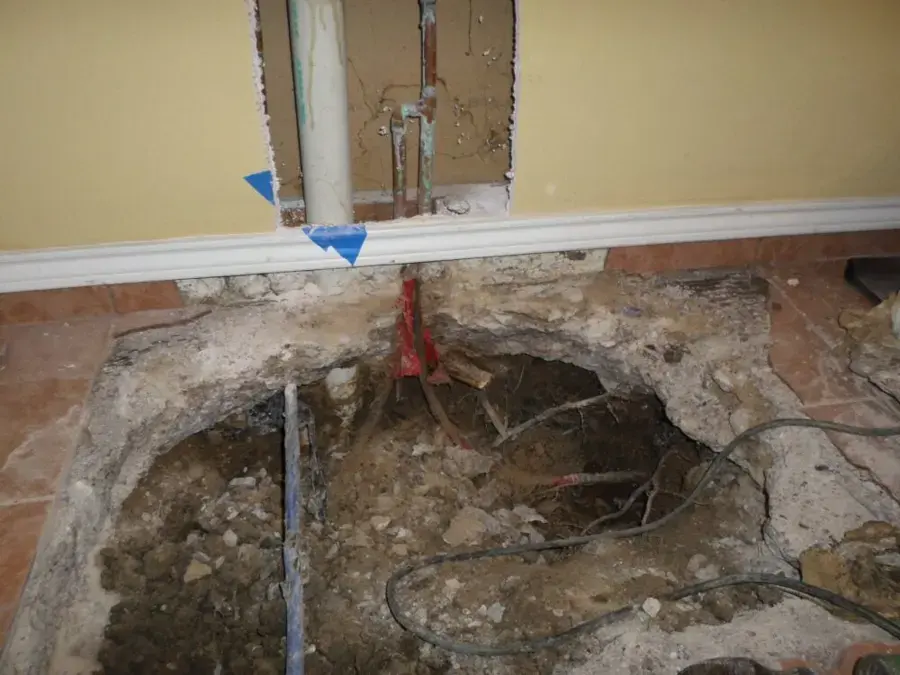Concrete slab opened to expose a leaking water line under a Naples tile floor